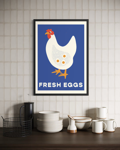 Framed poster of a chicken with 'Fresh Eggs' text on a tiled wall above kitchenware.