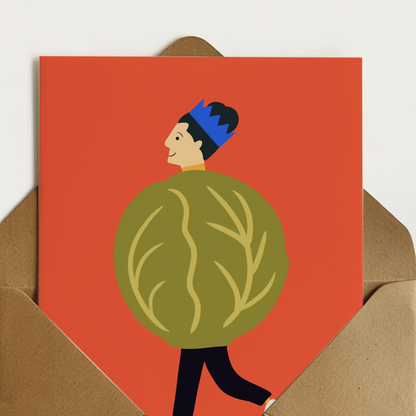 A6 greeting card with a bold orange-red background and an illustration of a person wearing a brussel sprout, shown standing in front of a brown kraft envelope.