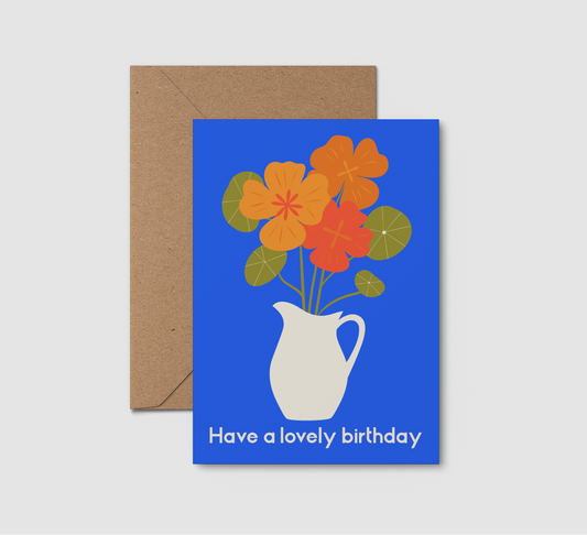 Greeting card with floral design and 'Have a lovely birthday' text, accompanied by a brown envelope on a light gray background.
