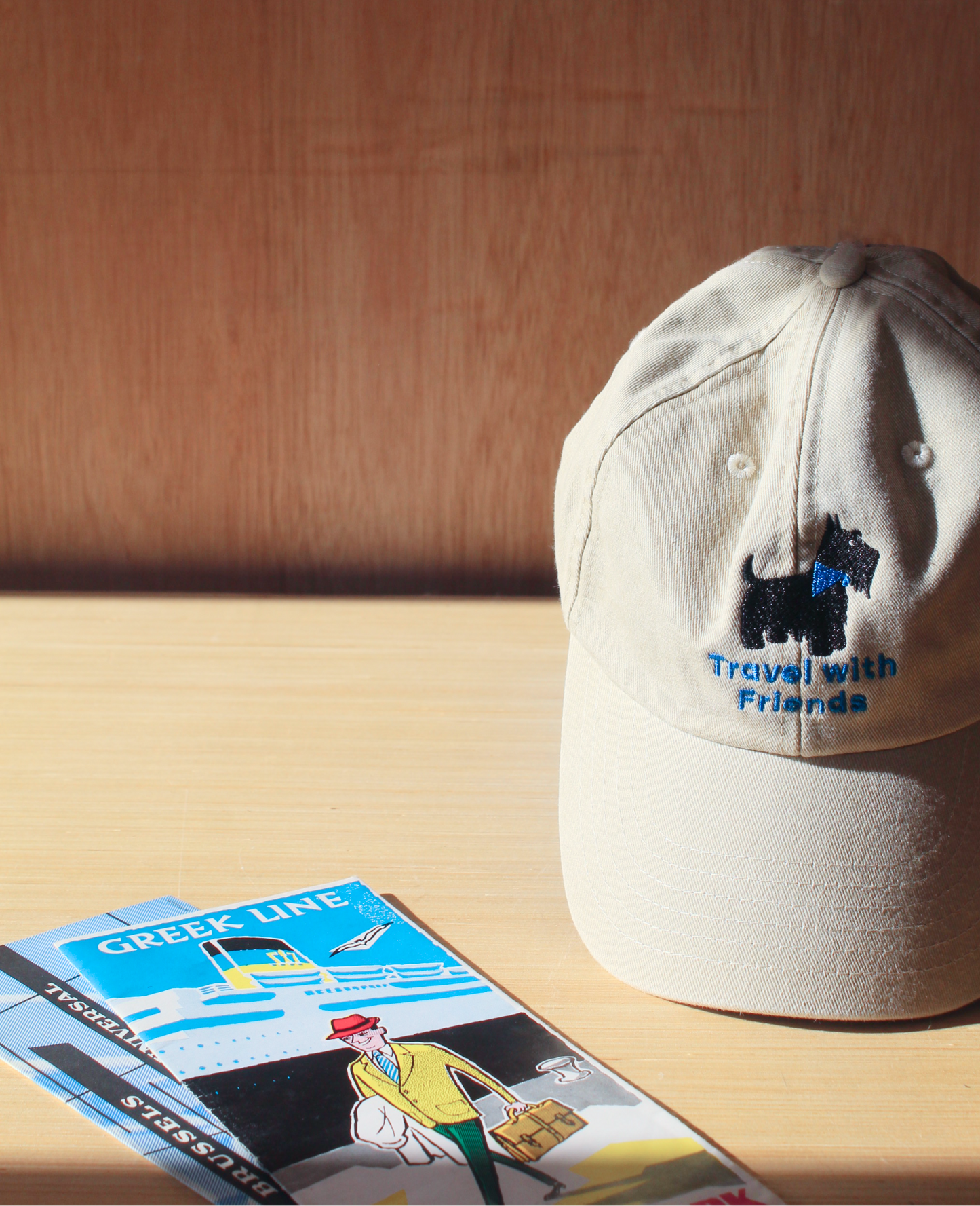 A light beige baseball cap with a blue embroidered 'Travel with Friends' logo and a black dog graphic. Fashion caps. Unisex caps. 